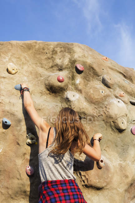 Teenage girl climbing up artificial rock — Stock Photo