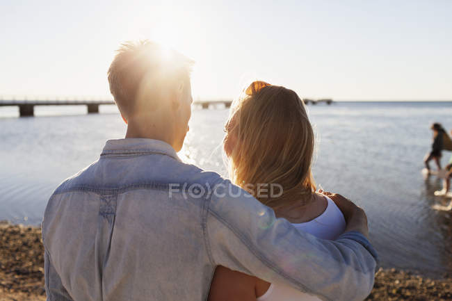 Uomo abbracciando donna in piedi sulla spiaggia — Foto stock