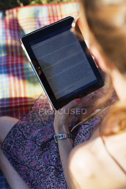 Жінка тримає електронного читача в парку — стокове фото