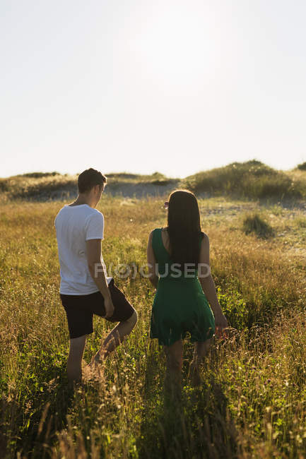 Casal andando no campo gramado — Fotografia de Stock