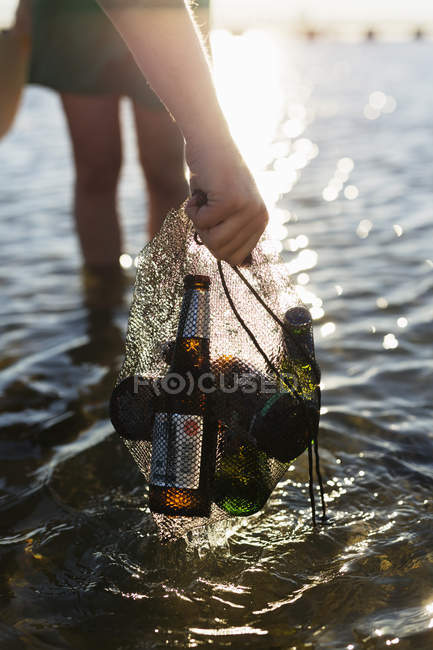 Mão segurando garrafas de cerveja na rede — Fotografia de Stock