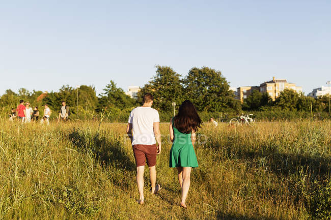 Casal andando no campo gramado — Fotografia de Stock