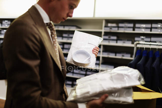 Salesman analyzing shirts in clothing store — Stock Photo