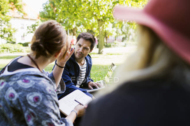 Freelancers discussing while sitting at park — Stock Photo