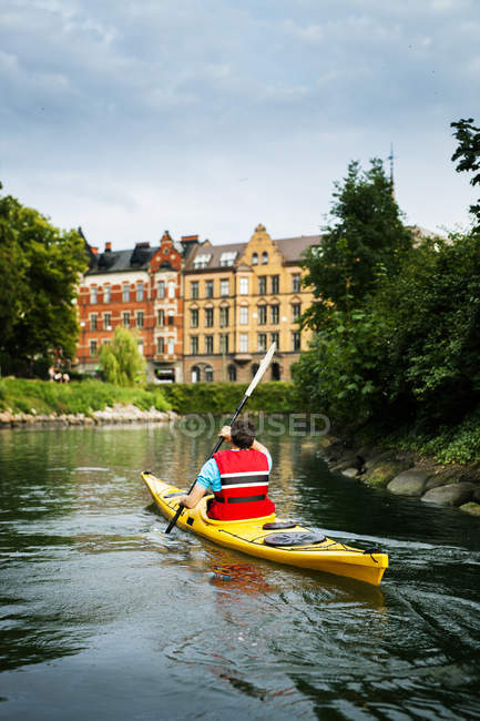 Man kayaking on river in city — Stock Photo
