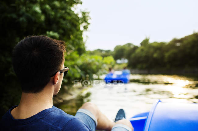 Man pedaling boat on river — Stock Photo