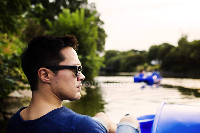Man looking away while pedaling boat — Stock Photo