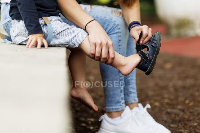 Madre che assiste il figlio nell'indossare sandalo — Foto stock