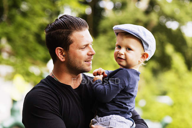 Homme portant son fils dans le parc — Photo de stock