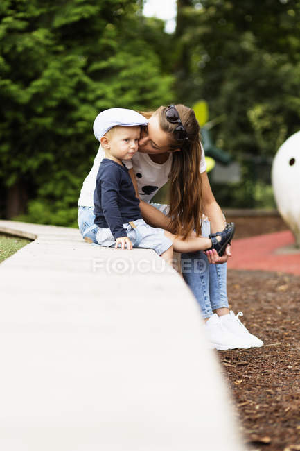 Woman assisting son in wearing sandal — Stock Photo