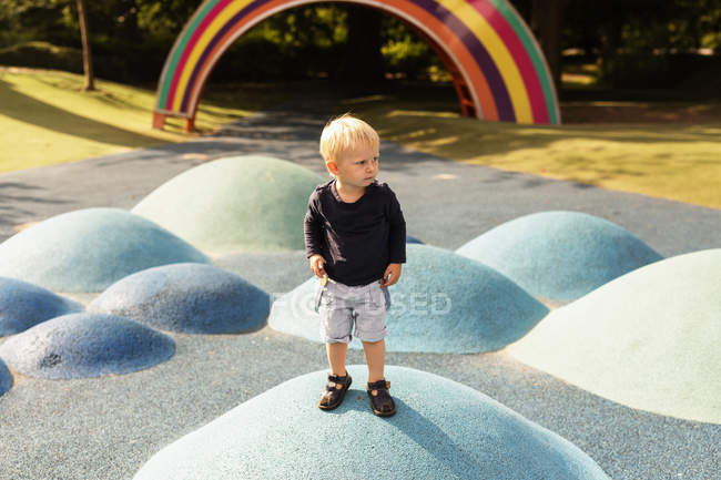 Хлопчик стоїть на штучному пагорбі на дитячому майданчику — стокове фото