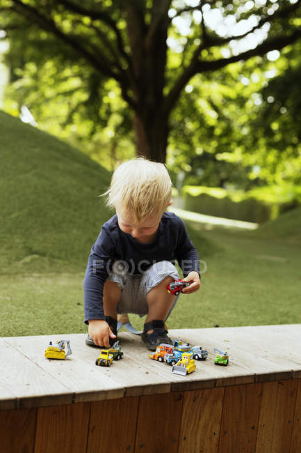 Мальчик играет с игрушечными машинами в парке — стоковое фото