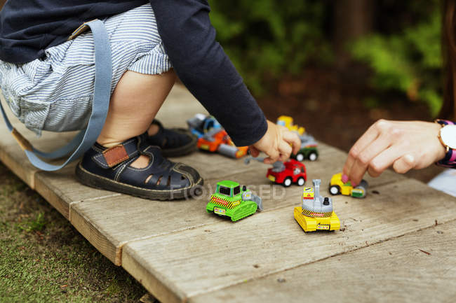 Niño y madre jugando con coches de juguete - foto de stock