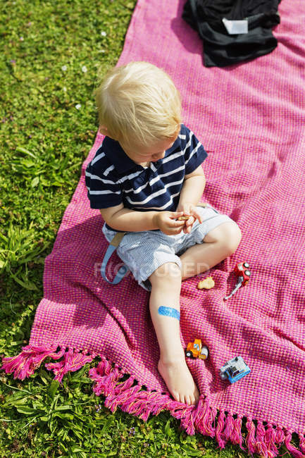 Мальчик держит печенье, сидя на столе для пикника — стоковое фото