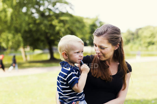 Mulher olhando para filho no parque — Fotografia de Stock