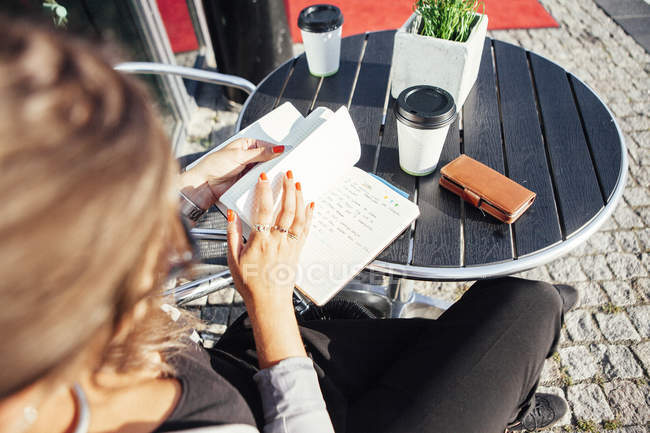 Деловая женщина читает дневник в кафе на тротуаре — стоковое фото