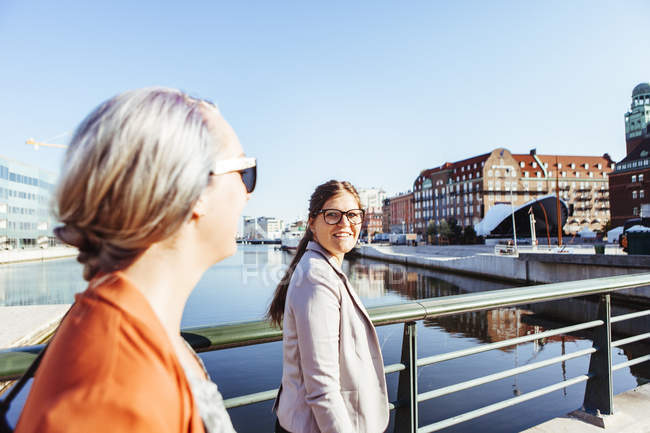 Businesswoman looking at colleague while walking on bridge — Stock Photo