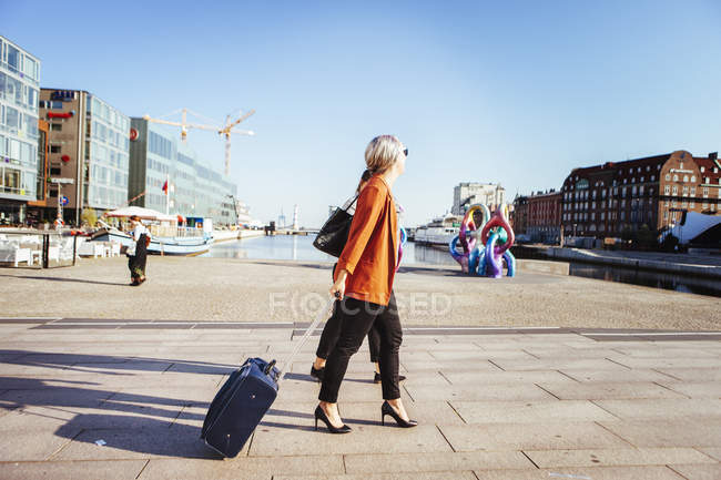 Businesswoman with luggage walking on city street — Stock Photo