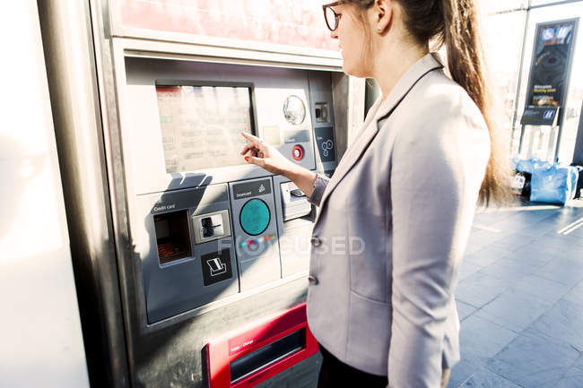 Businesswoman using ticket machine — Stock Photo