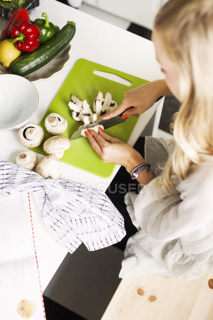 Mujer picando setas en la cocina - foto de stock
