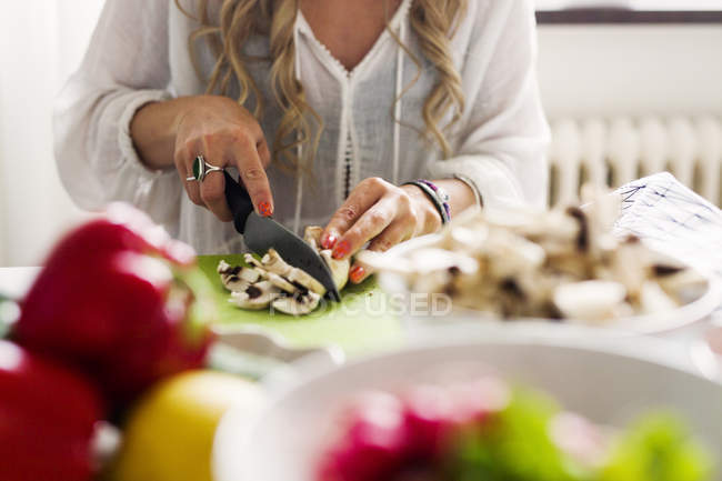Woman cutting mushrooms in kitchen — Stock Photo