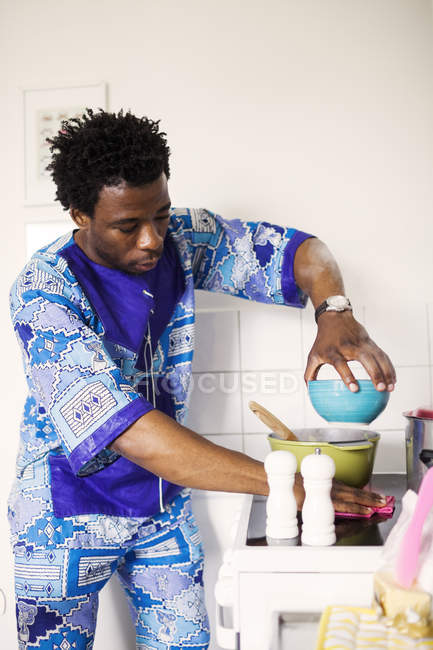 Человек вытирает плиту во время приготовления пищи — стоковое фото