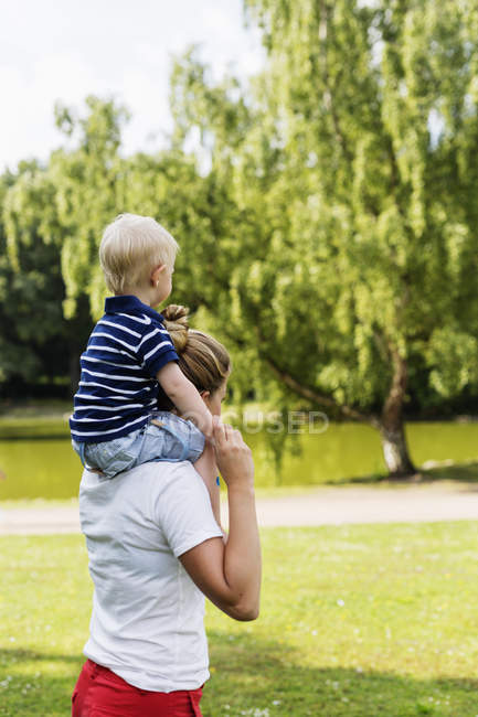 Женщина носит сына на плечах в парке — стоковое фото