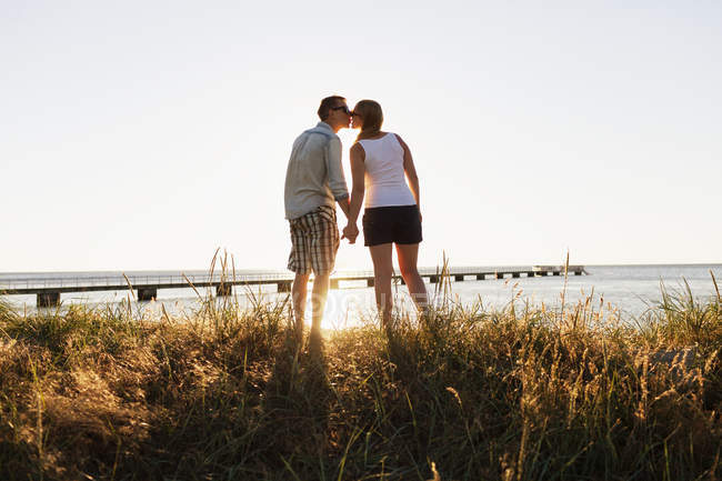 Hombre y mujer besándose en la playa - foto de stock