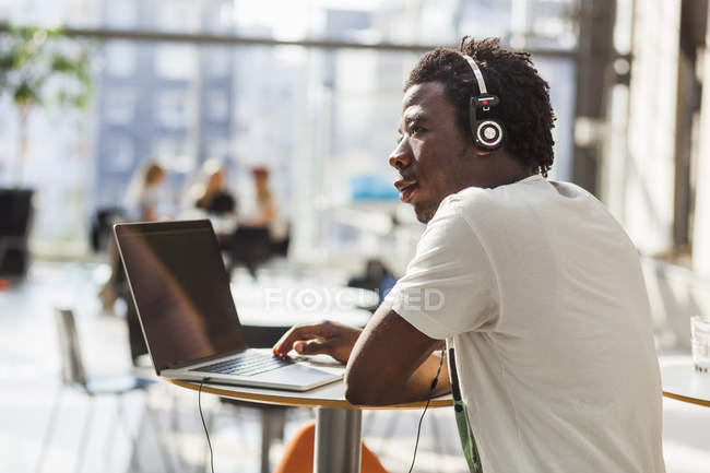 Estudiante universitario escuchar música a través de ordenador portátil - foto de stock