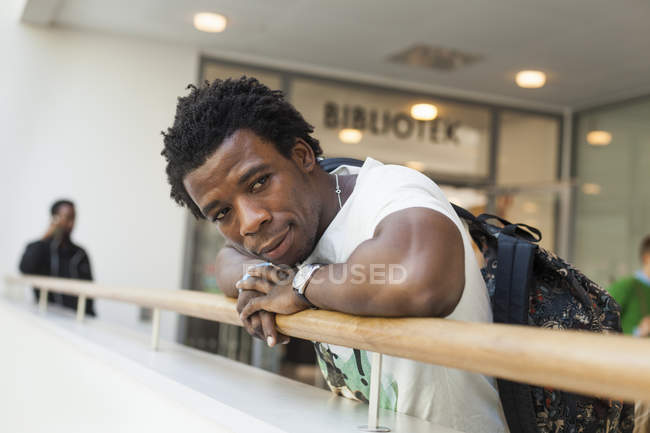 Hombre apoyado en barandilla en la universidad - foto de stock