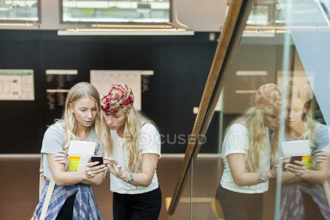 Étudiants utilisant un téléphone mobile sur les marches — Photo de stock