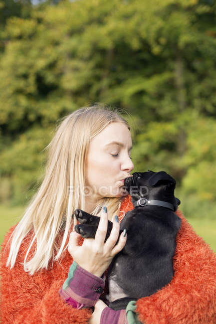 Женщина целует щенка на открытом воздухе — стоковое фото