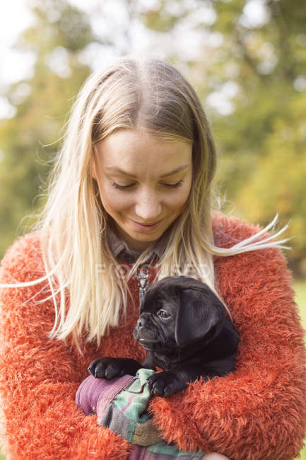 Woman holding puppy outdoors — Stock Photo