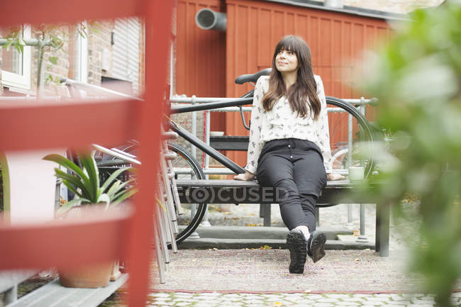 Frau sitzt auf Bank im Hinterhof eines Cafés — Stockfoto