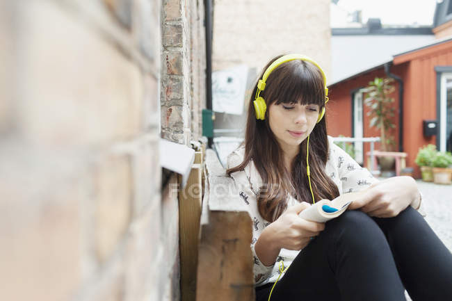 Жінка слухає музику під час читання книги — стокове фото