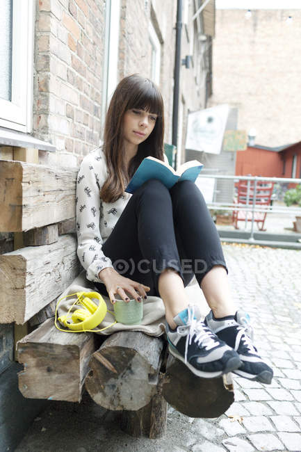 Woman reading book at cafe backyard — Stock Photo