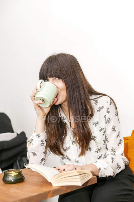 Frau mit Buch trinkt Kaffee — Stockfoto