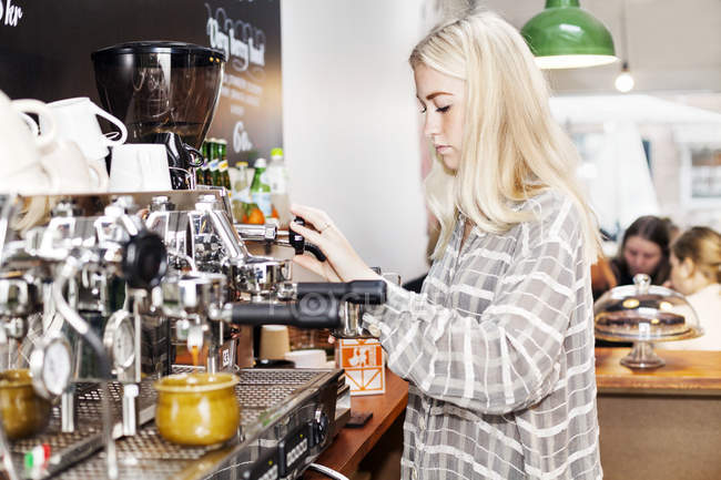 Young female barista making coffee — Stock Photo