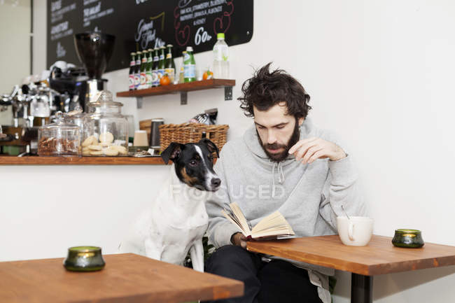 Собака з чоловіком читає книгу — стокове фото