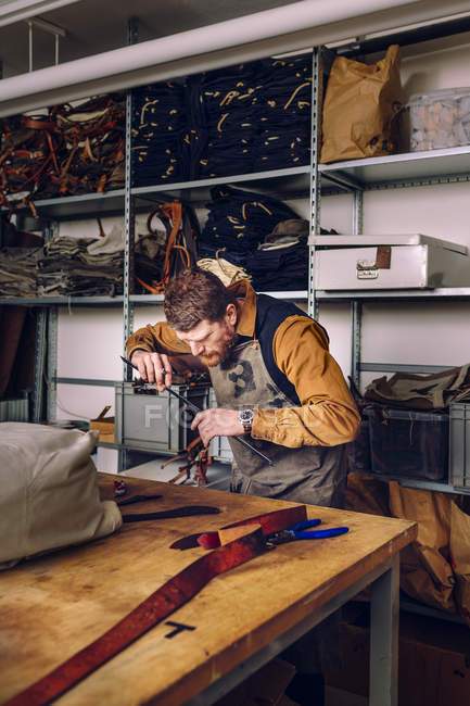 Мужчина на фабрике сумок — стоковое фото