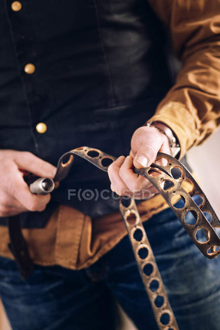 Travailleur tenant des ceintures en cuir — Photo de stock