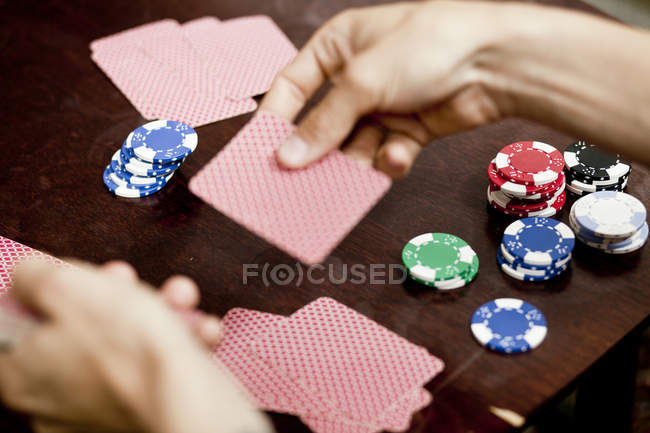 Manos de hombre jugando a las cartas en casa - foto de stock