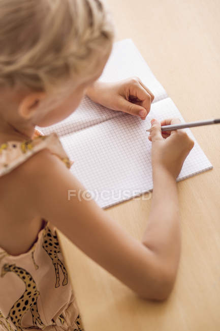 Chica escribiendo en libro - foto de stock