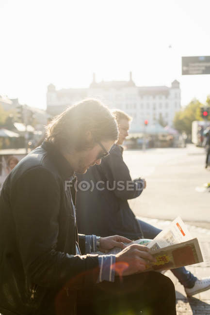 Businessman reading newspaper on sidewalk — Stock Photo