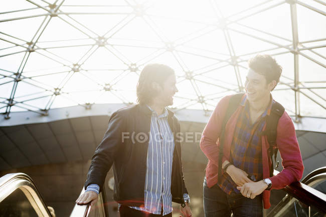 Lächelnde Männer reden auf Rolltreppe — Stockfoto