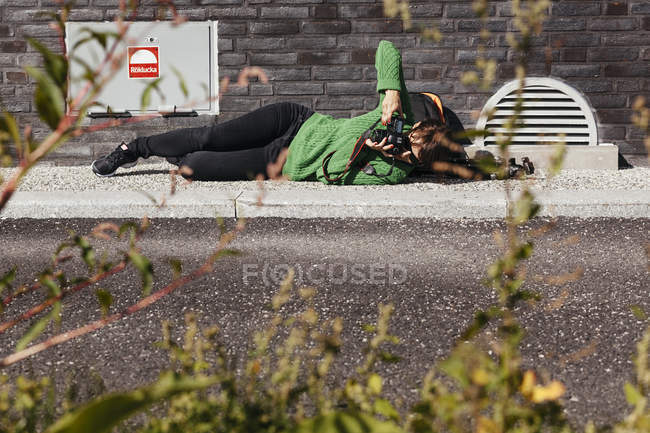 Woman photographing while lying — Stock Photo
