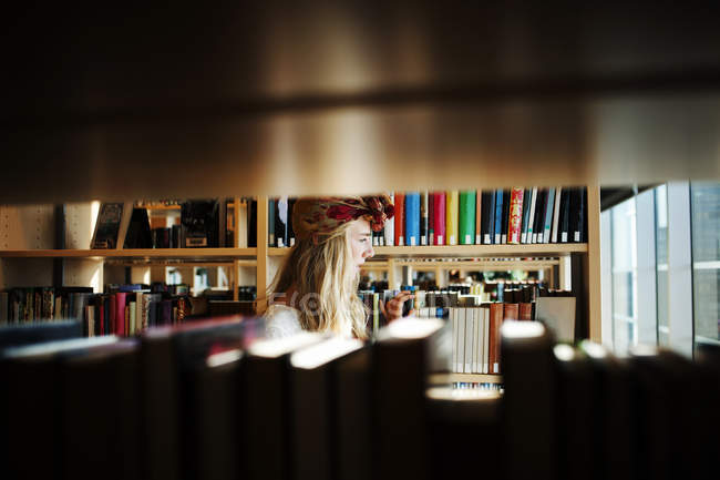 Jovem estudante universitário em biblioteca — Fotografia de Stock