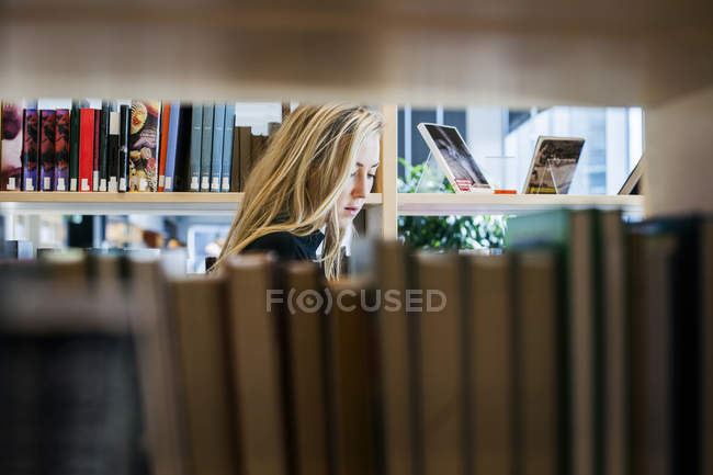 Woman seen through bookshelf — Stock Photo