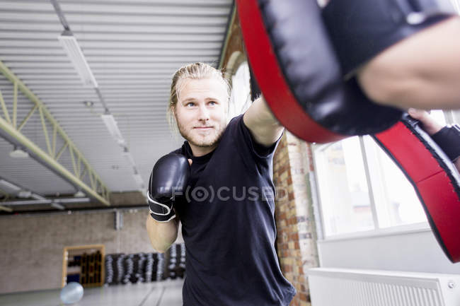 Jovem com treinador praticando boxe — Fotografia de Stock