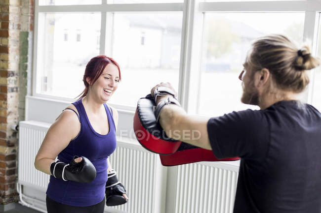 Woman with male trainer practicing boxing — Stock Photo